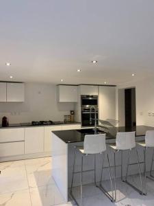 a kitchen with white cabinets and white stools at Superbe appartement JO 2024 in Plaisir