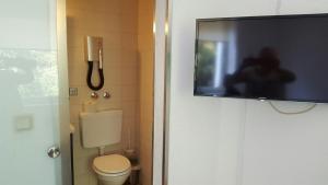a bathroom with a toilet and a flat screen tv at Hotel Bergische Schweiz in Velbert