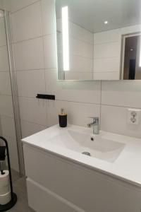een witte badkamer met een wastafel en een spiegel bij Helsesenterveien 7N in Haugland