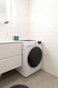 een witte wasmachine in een badkamer naast een wastafel bij Helsesenterveien 7N in Haugland