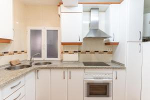 a kitchen with white cabinets and a sink at Trendy Homes Catedral in Almería