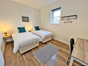 a bedroom with two beds and a table and a window at Immaculate 2-Bed Apartment Town Centre in Cheltenham