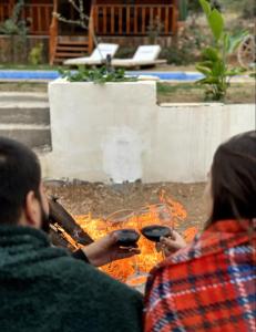 Ein Mann und eine Frau, die Weingläser über einem Feuer halten. in der Unterkunft Flow Urla in Izmir