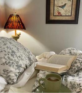 a book on a bed with a lamp and a cup of coffee at Truly Central Private Guest House in Nashville