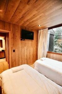 a bedroom with two beds and a tv on the wall at Moon Box in San Carlos de Bariloche