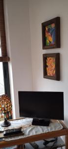 un monitor de ordenador en un escritorio con tres pinturas en Mirar&Soñar, en Chantada