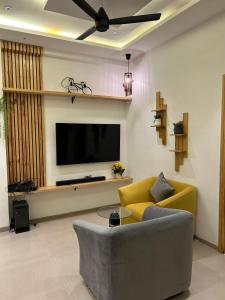 a living room with a yellow couch and a flat screen tv at Andaz Luxe Apartment. in Indore
