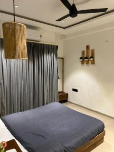 a bedroom with a blue bed and a ceiling fan at Andaz Luxe Apartment. in Indore