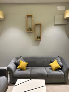 a living room with a gray couch with yellow pillows at Andaz Luxe Apartment. in Indore