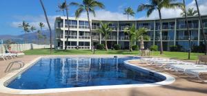 a resort with a pool and chairs and a building at Ocean, Beachfront OASIS in Waianae