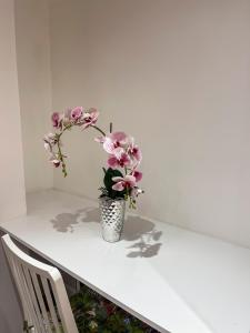 een witte tafel met een vaas met roze bloemen erop bij Ensuite Room with Jacuzzi in Londen