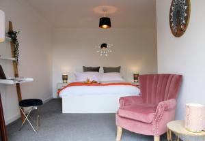 a bedroom with a bed and a pink chair at Ely Elegance in Ely