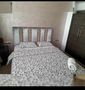 a bedroom with a bed with a black and white comforter at Urbain place masira in Casablanca