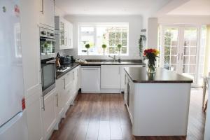 a kitchen with white cabinets and a wooden floor at Ely Elegance in Ely