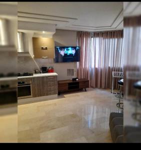 a living room with a kitchen with a tv on the wall at Urbain place masira in Casablanca