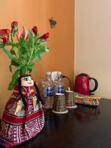 um vaso com flores sobre uma mesa com garrafas de água em Panorama B&B em Machu Picchu