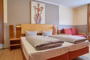 1 dormitorio con 2 camas y un jarrón en la pared en Hotel Römer, en Günzburg