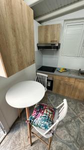 a small kitchen with a white table and a chair at LE NID d'oiseau studio meublé climatisé chez l'habitant in Deshaies