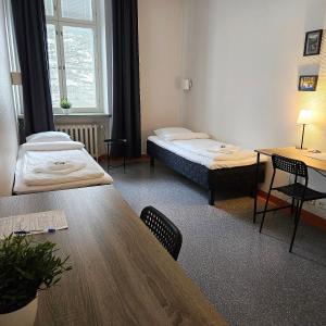 a room with two beds and a table and chairs at Hostel Bjorkenheim in Seinäjoki