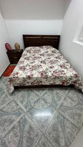 a bed with a floral comforter on it in a bedroom at LE NID d'oiseau studio meublé climatisé chez l'habitant in Deshaies