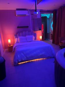 a bedroom with a large bed with purple lighting at Crownn - Spa Privatif in Fontenay-sous-Bois