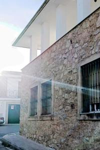 um edifício de pedra com duas janelas do lado em Casa Rural Las Parras 48 em Malpartida de Cáceres