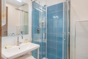 a bathroom with a sink and a shower with blue tiles at Residenze Asproni Serviced Apartments in Cagliari