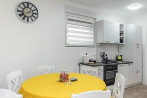 uma cozinha com uma mesa amarela e armários brancos em Apartman Diva Jana Divčibare em Divčibare
