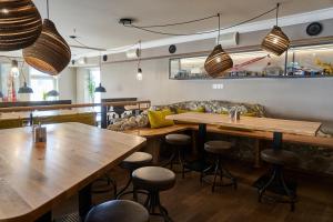 a restaurant with wooden tables and a couch at Hotel Römer by Fairway Hotels in Günzburg