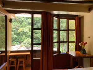a room with a large window and a table and chairs at Panorama B&B in Machu Picchu