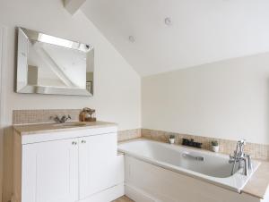La salle de bains blanche est pourvue d'un lavabo et d'un miroir. dans l'établissement Morlais, à Beaumaris