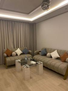 a living room with two couches and a glass table at شقة مريحة بتصميم انيق ودخول ذكي in Riyadh