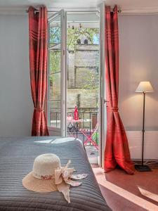 una camera da letto con tende rosse e un cappello su un letto di Centre Palais des Papes-Balcon B1 Clim - 123avignon ad Avignone