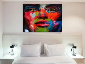 a painting of a woman is hanging above a bed at Vistas&Luz Zona Lycee 5 minutos al centro in Andorra la Vella