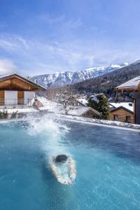 basen z niebieską wodą z górami w tle w obiekcie Hotel Ravelli Luxury Spa w mieście Mezzana