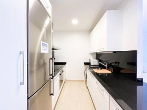 a kitchen with white cabinets and a stainless steel refrigerator at Vistas&Luz Zona Lycee 5 minutos al centro in Andorra la Vella