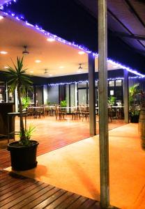 Spinifex Hotel في ديربي: غرفة بها طاولات وكراسي وأضواء أرجوانية