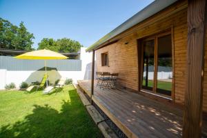 eine Holzterrasse mit Stühlen und einem Sonnenschirm in der Unterkunft Chalet d'Aroeira in Corroios