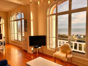 sala de estar con TV y ventanas grandes en VILLA ALBION, en Hautot-sur-Mer