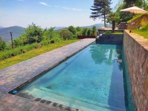 a swimming pool with blue water and a retaining wall at Masía La Garrotxa in Olot