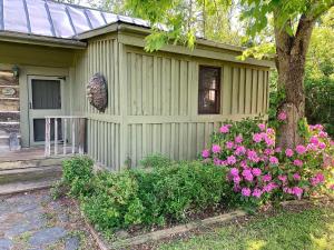 a green house with pink flowers next to a tree at Heartstone Country Retreat in Buena Vista