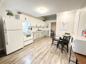 una cucina con elettrodomestici bianchi, tavolo e sedie di Gorgeous Condo in SJ w Coffee Wi-FI a Saint John