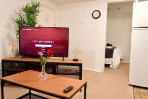 a living room with a television and a vase of flowers on a table at NEW Gorgeous Space in Moose Jaw Coffee Parking 4k Smart TV in Moose Jaw