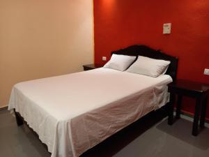 a bedroom with a large white bed with a red wall at Hospedaje casa Yuca in Valladolid