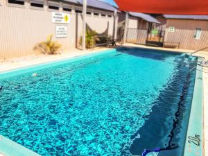 una piscina de agua azul frente a un edificio en Spinifex Hotel, en Derby