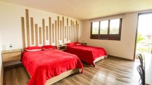 a bedroom with two beds with red sheets and a window at Hotel rio de piedras in Tuta