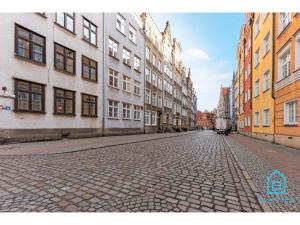 a cobblestone street with tall buildings in a city at Libertas Premium Apartment at Old Town Gdansk in Gdańsk