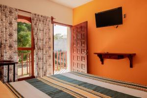 Schlafzimmer mit einem Bett, einem TV und einem Fenster in der Unterkunft Casa Triz in Puerto Escondido