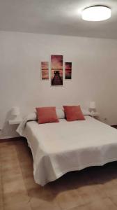 a bedroom with a large white bed with three pictures on the wall at Amplio apartamento recién reformado in Tejina