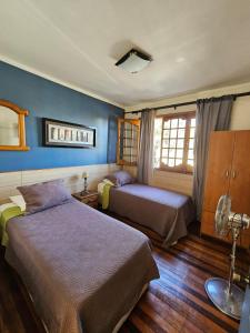 two beds in a room with blue walls at Hostal el Parron in Rancagua